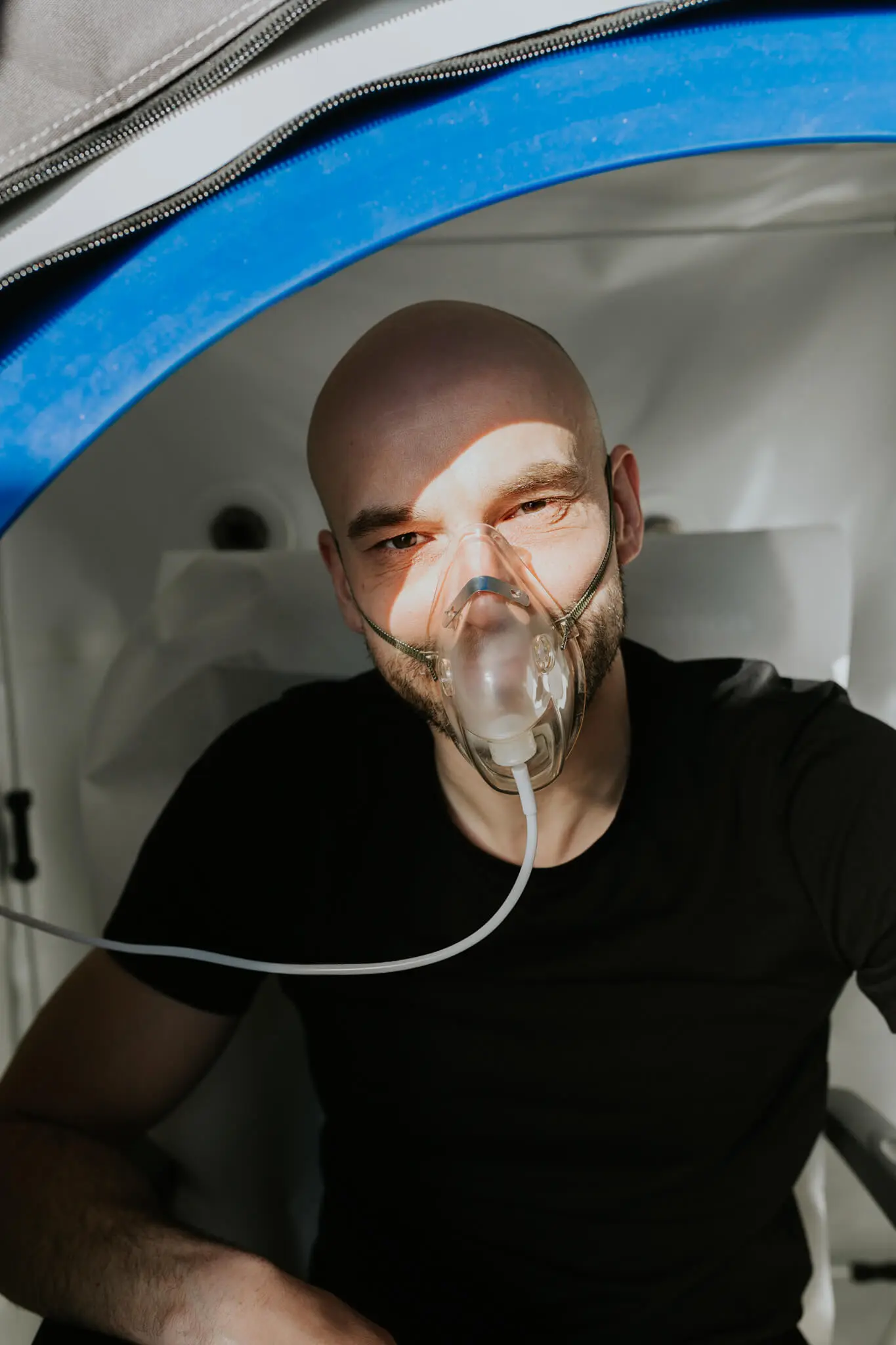 Uśmiechnięty pacjent z maseczką tlenową podczas zabiegu tlenoterapii hiperbarycznej w Si Longevity Center, Szczecin.