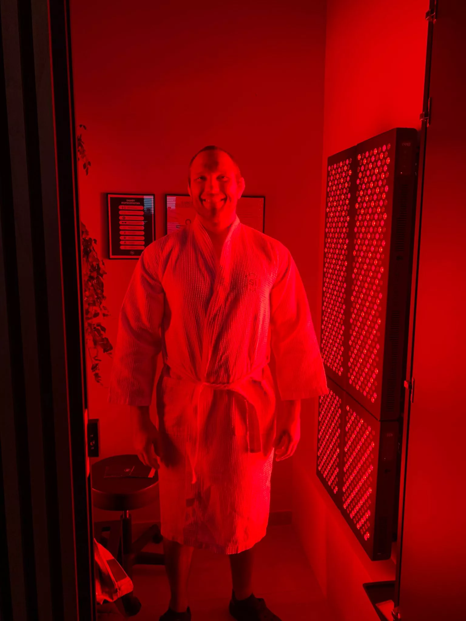 Uśmiechnięty mężczyzna w Si Longevity Center przygotowuje się do sesji terapii światłem czerwonym i podczerwonym, która wspomaga sportowców w poprawie wyników.